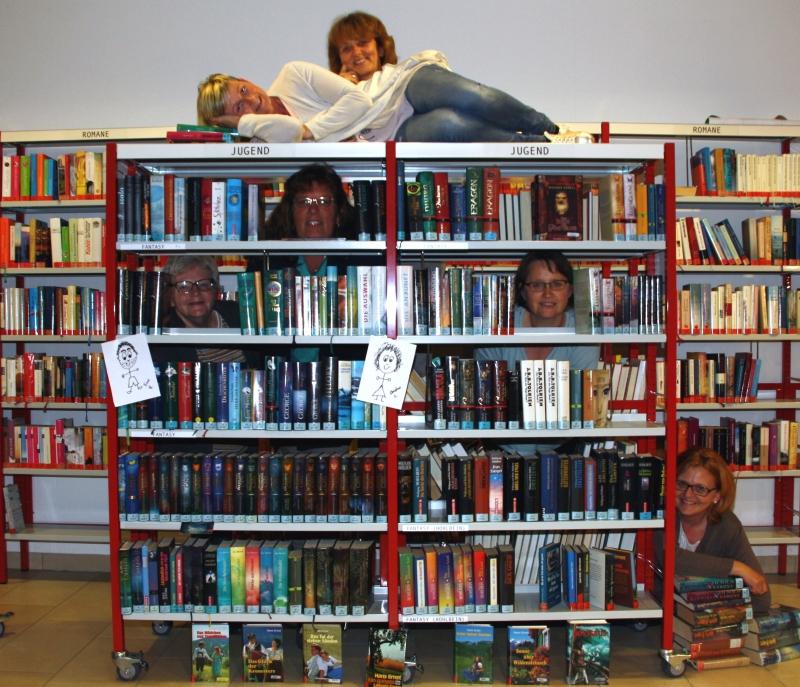 Büchereiteam auf und hinter Buchregal - durch buchfreie Bereiche durchschauend